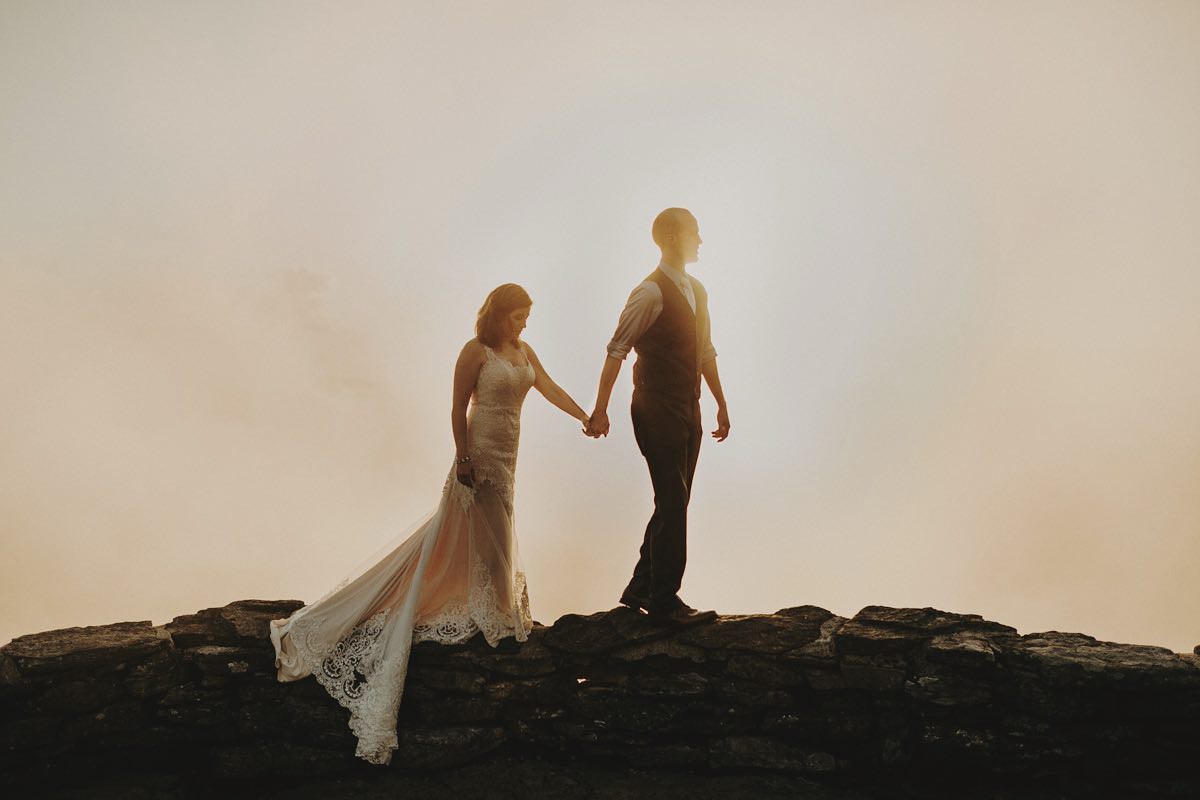 Asheville elopement image of a wedding couple walking along a rock wall at Craggy Gardens in Asheville North Carolina.
