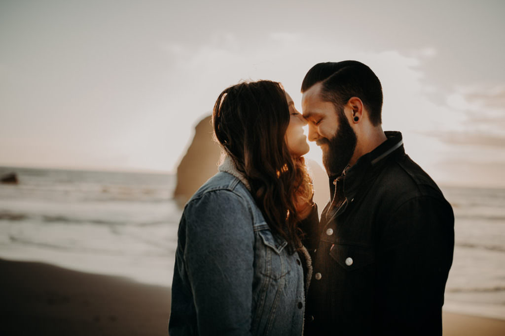 An Asheville elopement photographer captured an incredible backlit photo of a dark haired couple at Cannon Beach. The image links to the photographer's couples portfolio.